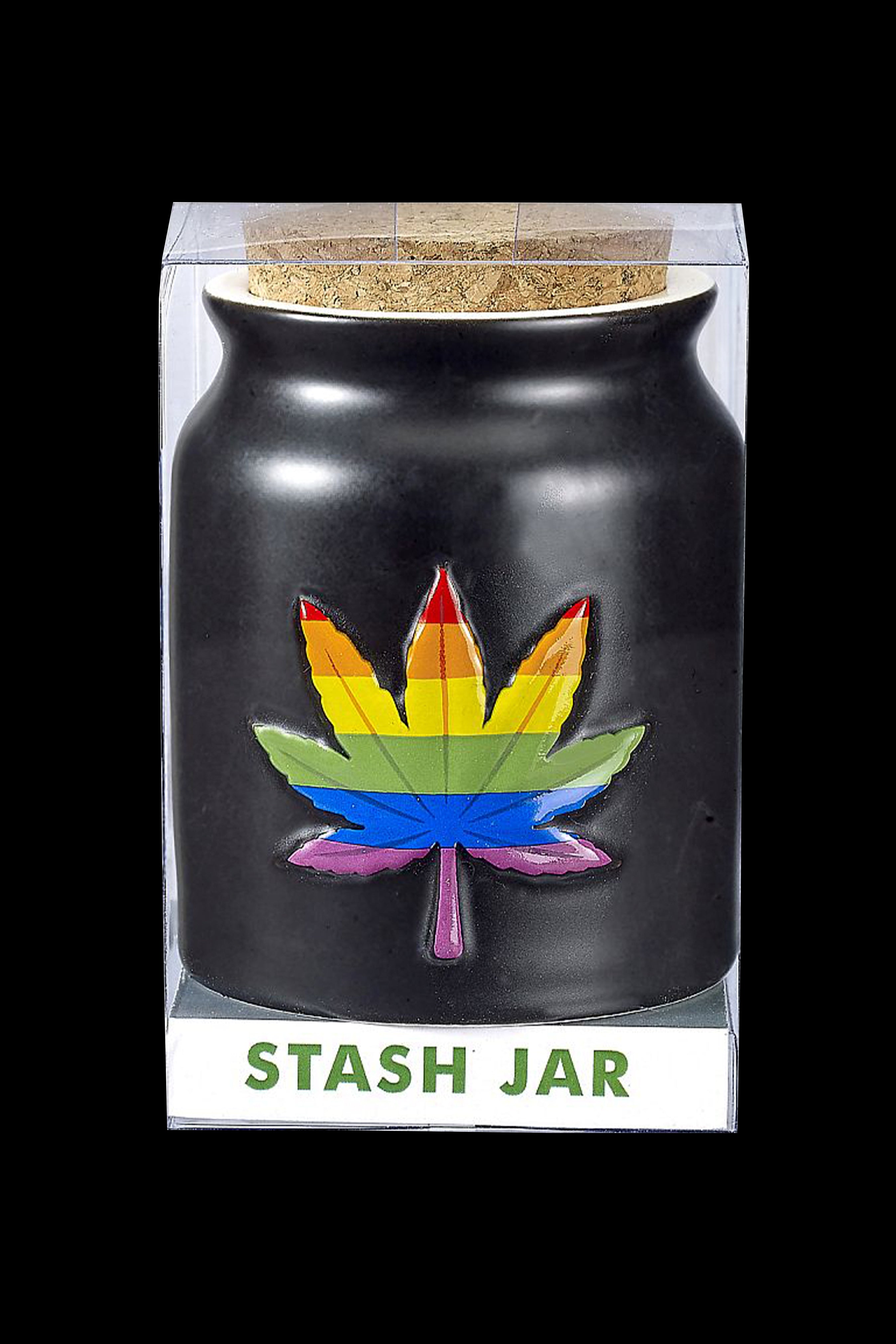 Black cannabis stash jar with a rainbow marijuana leaf emblem, displayed in a clear box labeled “STASH JAR”.