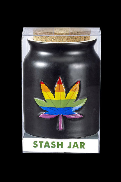 Black cannabis stash jar with a rainbow marijuana leaf emblem, displayed in a clear box labeled “STASH JAR”.