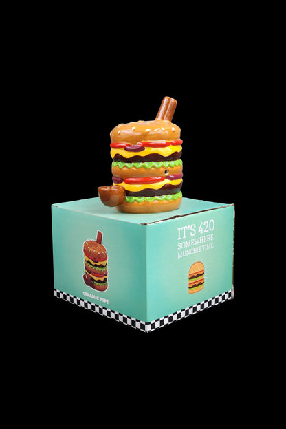 A boxed ceramic smoking pipe shaped like a colorful burger, with packaging reading ""It's 420 Somewhere, Munchie Time!""