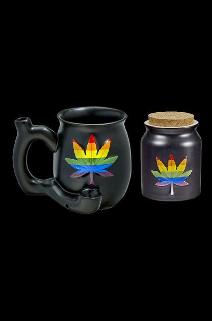 Black cannabis smoking pipe shaped like a mug and a matching storage jar with rainbow leaf designs, isolated on a black background.