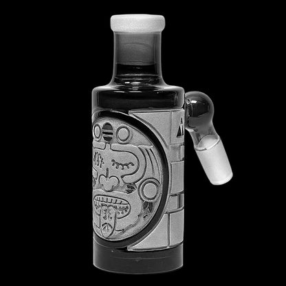 Close-up front view of the Milkyway Maya Wet Ash Catcher showing a carved circular Mayan face motif and a 45° male teal angled joint against a black background.