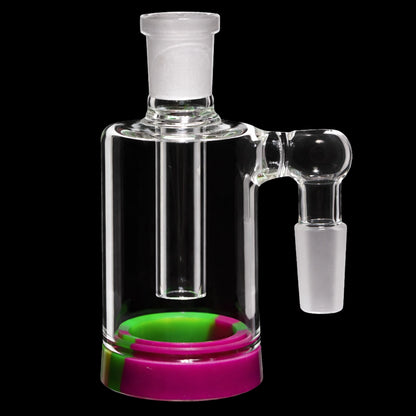 Close-up front view of the Smoke Cartel 4-inch Silicone Base Reclaim Ash Catcher - 90 degree - 14mm showing the clear glass chamber and joint with a neon yellow and pink silicone base against a black background.