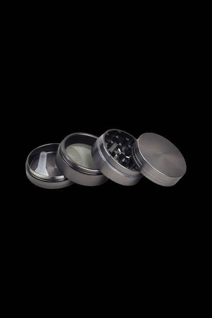 Black four-piece cannabis grinder disassembled on a black background.