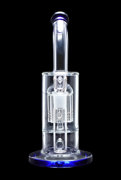 Clear glass dab rig with intricate percolators, illuminated with blue light against a black background.