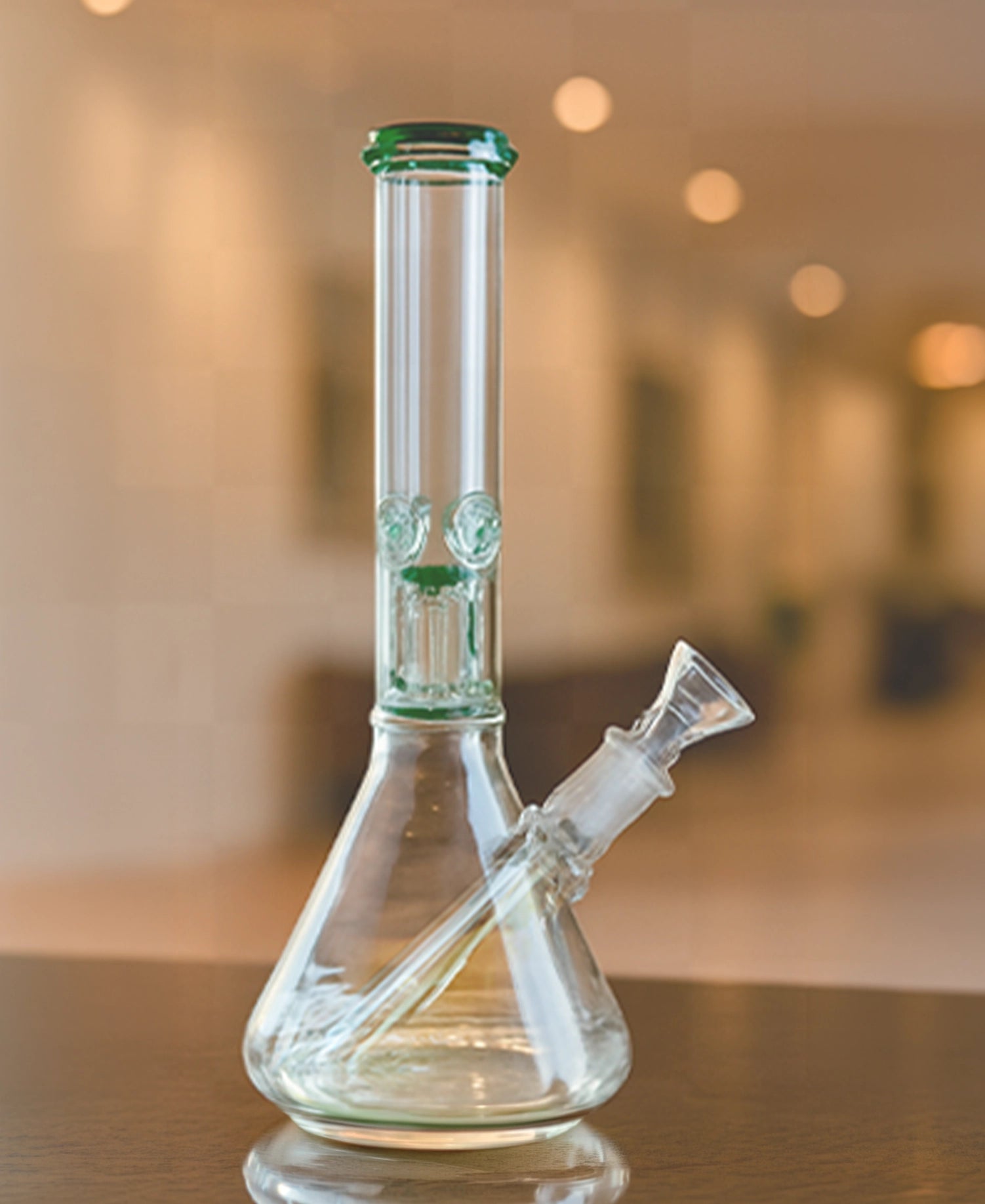Close-up, angled view of The Stash Shack 6 Arm Perc Beaker Bong showing its clear glass beaker base, tilted downstem, and tall straight neck with green-rim accents.