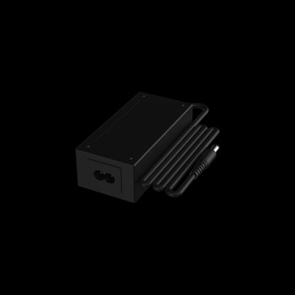 Angled close-up of the black Switch™ Charging Cable and Adapter showing the rectangular adapter block, coiled cable, and barrel connector against a pitch‑black background