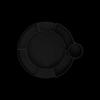 Top-down close-up of the black Switch™ Silicone Base showing its circular compartments and subtle raised rim against a dark background