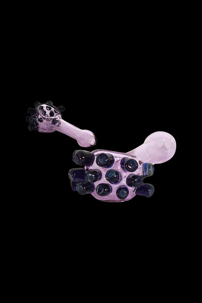 Pink glass bubbler with dark purple bubbles, floating against a black background.