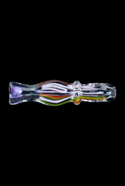 Horizontal close-up of the Smoke Cartel Frit Rasta One Hitter - 3 in., a clear glass tube with swirled pink, green, yellow, and red frit accents against a black background