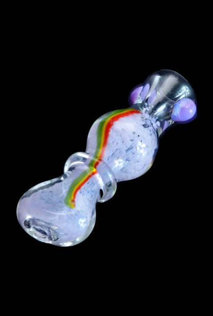 Angled close-up of the Smoke Cartel Frit Rasta One Hitter - 3 in. showing its clear glass body with a central white fritbed and a red-yellow-green rasta stripe.