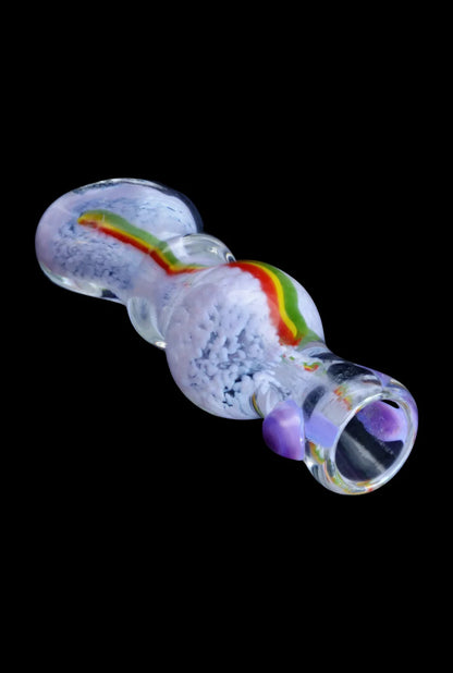 Angled close-up of the Smoke Cartel Frit Rasta One Hitter - 3 in., showing its clear glass body with white frit texture and a red-yellow-green rasta stripe.