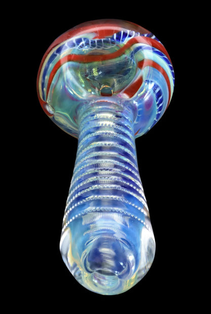 Low-angle close-up of the Smoke Cartel Engraved Fumed Spoon Pipe - 3 in., showing its ribbed translucent blue neck and rounded bowl with red and blue swirls.