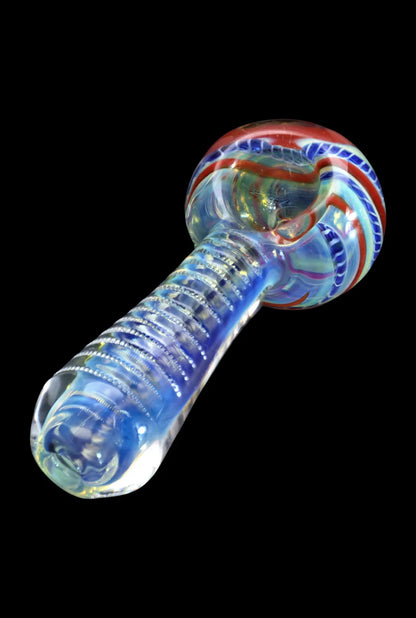 Angled close-up of the Smoke Cartel Engraved Fumed Spoon Pipe - 3 in., showing its iridescent blue handle with ribbed engraving and a red-and-white swirled bowl against a black background