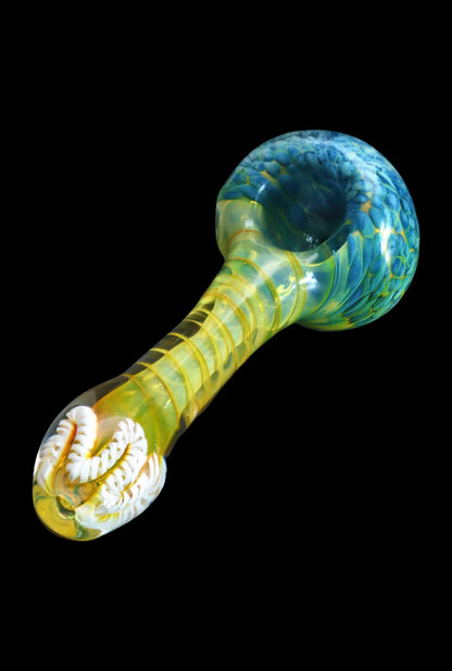 Angled close-up of the Smoke Cartel Twisting Frit Spoon Pipe - 3 in., showing a green-blue mottled bowl and a translucent yellow, spiral-textured stem on black background
