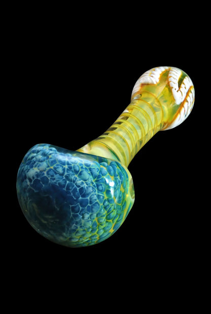 Angled close-up of the Smoke Cartel Twisting Frit Spoon Pipe - 3 in., showing its blue frit bowl, yellow twisted neck, and glossy black background