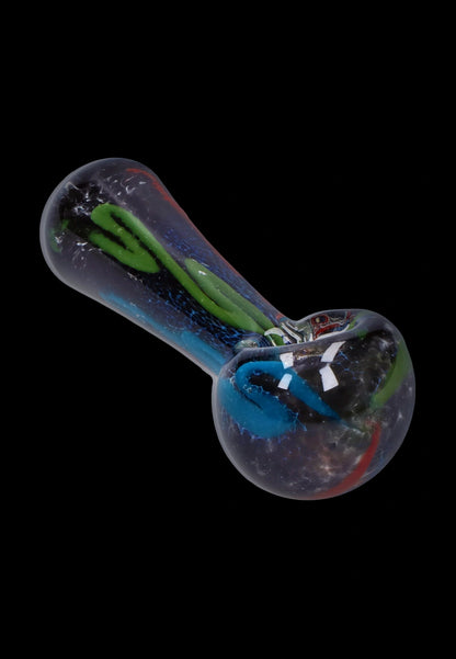 Angled close-up of the Smoke Cartel Color Frit Spoon Pipe - 3 in., showing its clear glass body with green and blue inner trails against a black background