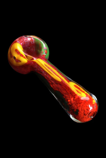 Angled close-up of the Smoke Cartel Color Frit Spoon Pipe - 3 in. showing red, yellow, and green swirls on a black background