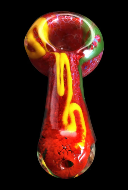 Top-down view of the Smoke Cartel Color Frit Spoon Pipe - 3 in. showing a glossy red bowl and stem with yellow squiggles and green accents on a black background