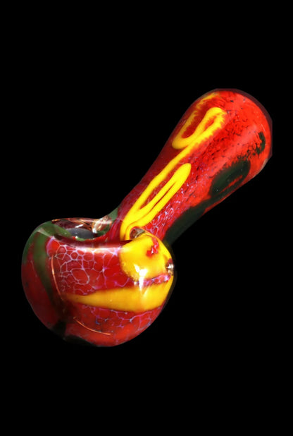 Angled close-up of the Smoke Cartel Color Frit Spoon Pipe - 3 in. showing red glass with yellow swirls and a pebble-textured bowl against a black background