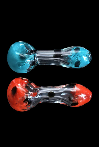 Top-down view of two Smoke Cartel Colour Frit with Dots Spoon Pipe - 2.5 in. glass spoons, one blue-green and one red, set against a black background.