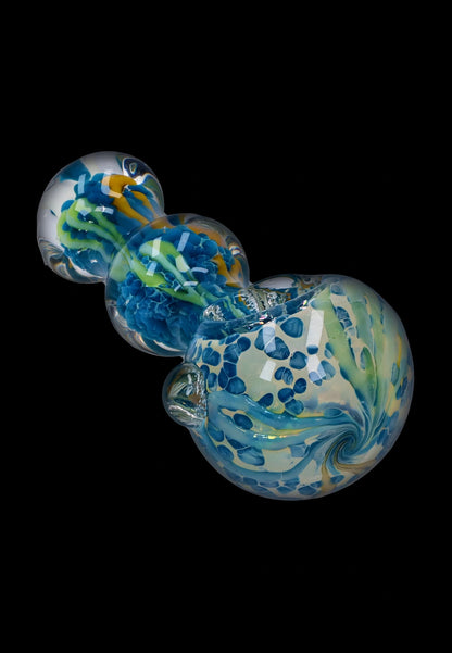 Angled close-up of the Smoke Cartel Fancy Frit Spoon Pipe - 3.5 in. showing swirled blue, green, and yellow frit patterns against a black background