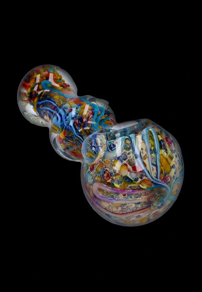 Angled close-up of the Smoke Cartel Fancy Frit Spoon Pipe - 3.5 in. showing swirling multicolored frit patterns under clear glass on a black background