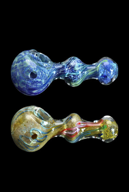 Top-down view of two Smoke Cartel Fancy Frit Spoon Pipe - 3.5 in. handblown glass spoons on a black background, the top in swirled milky blues and greens and the bottom in gold tones with red and blue accents.
