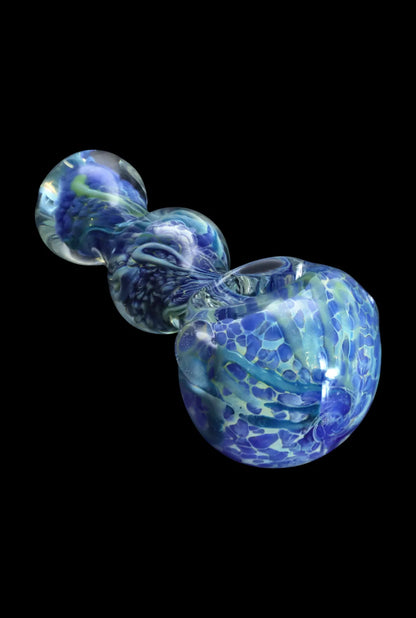 Angled close-up of the Smoke Cartel Fancy Frit Spoon Pipe - 3.5 in. showing swirled blue and green frit patterns against black.