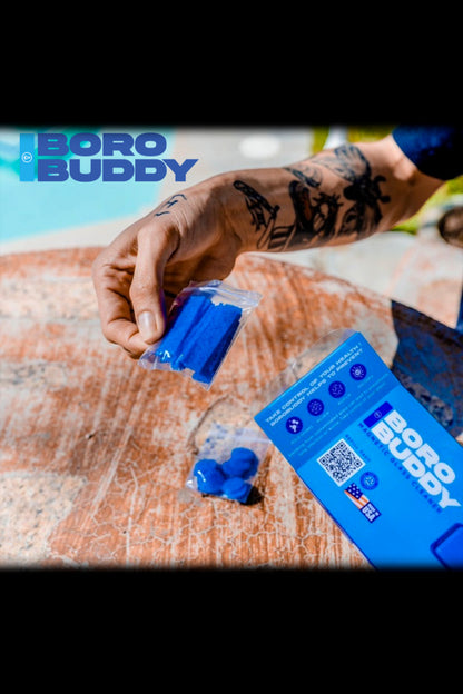 A person's hand holding blue cannabis wax and a box labeled “Boro Buddy” over a turquoise swimming pool.