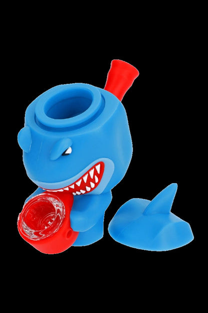 Blue shark-shaped silicone bubbler with a red mouthpiece and bowl containing reddish-brown cannabis.