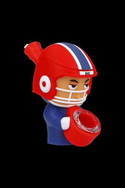Red football player figurine with a glass pipe attached, branded “DHC”.