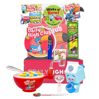 Front view of the “Wake N’ Bowl” Smoking Box display with a red cereal-bowl pipe, blue milk-carton figure, glass attachments and colorful branded backdrop.