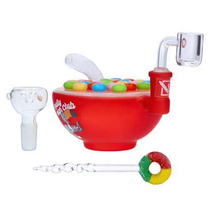Side view of the red “Wake N’ Bowl” Smoking Box with a candy-topped lid, clear glass mouthpiece and colorful dab tool.