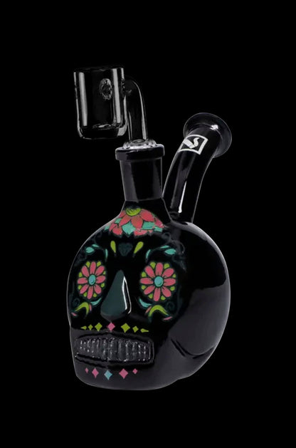 Black glass skull rig with colorful floral Day of the Dead-inspired design, featuring a downstem and mouthpiece.
