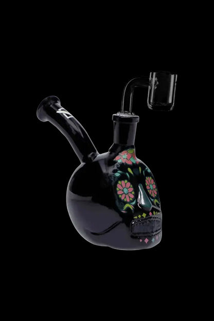 Black glass water pipe shaped like a sugar skull with colorful floral details, accompanied by a glass downstem.