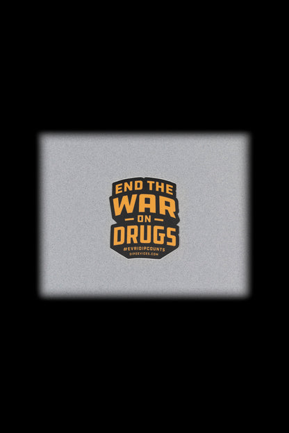 A square, textured gray background displays a circular badge with the text "END THE WAR ON DRUGS" and "#EVDIPCOUNTS" with a website address below.