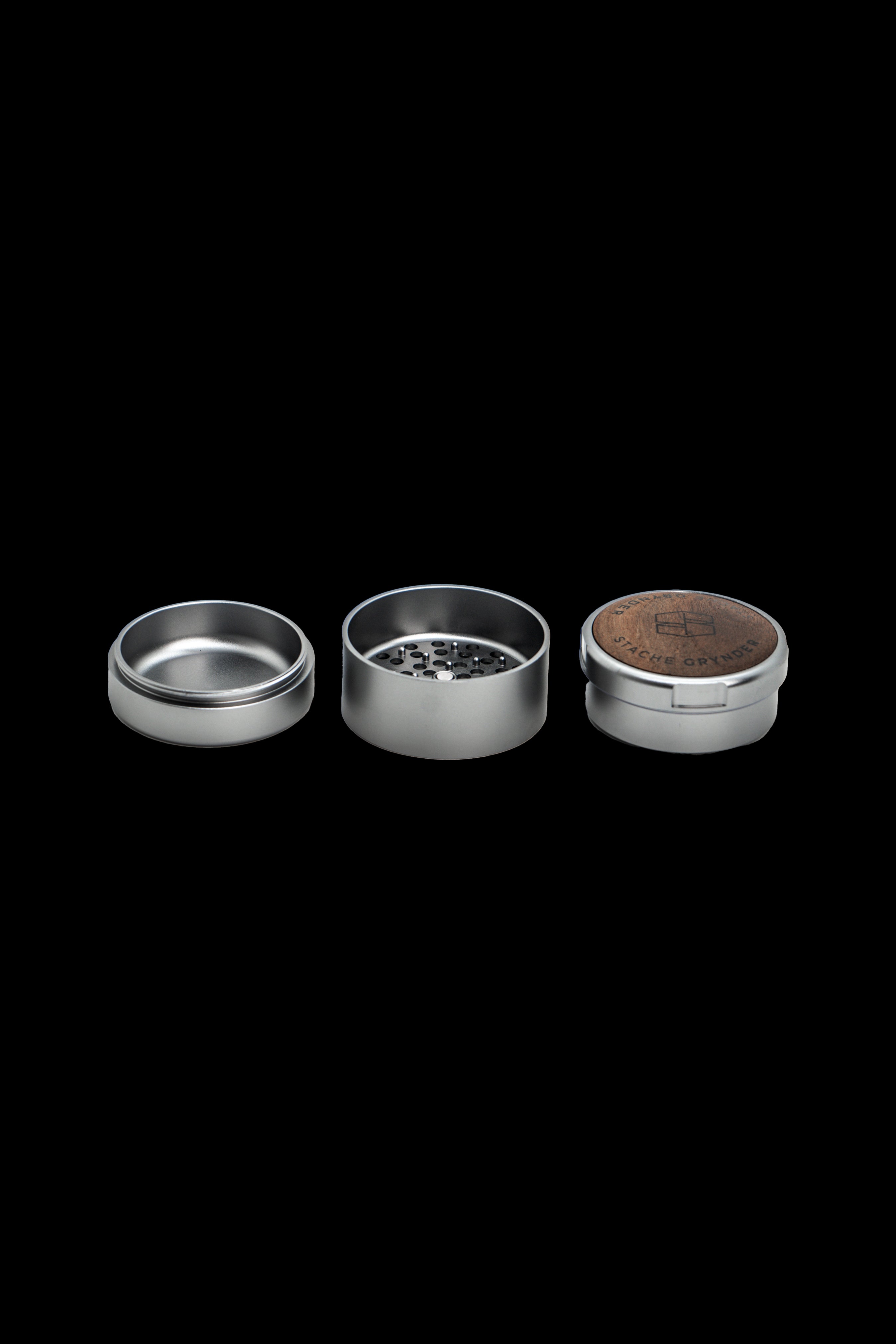 Metal grinder disassembled into three parts on a black background.