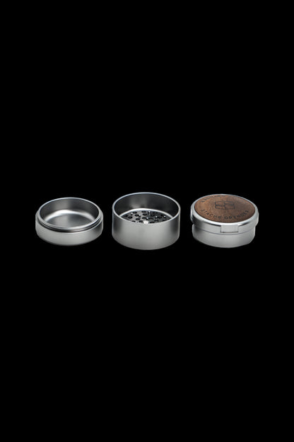 Metal grinder disassembled into three parts on a black background.