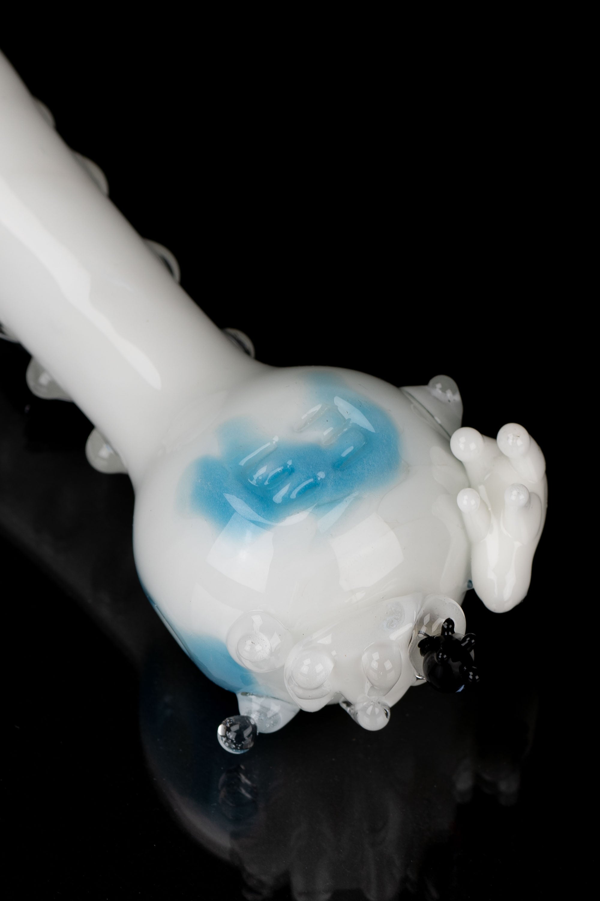 Blue and white glass water pipe emitting vapor against a black background.
