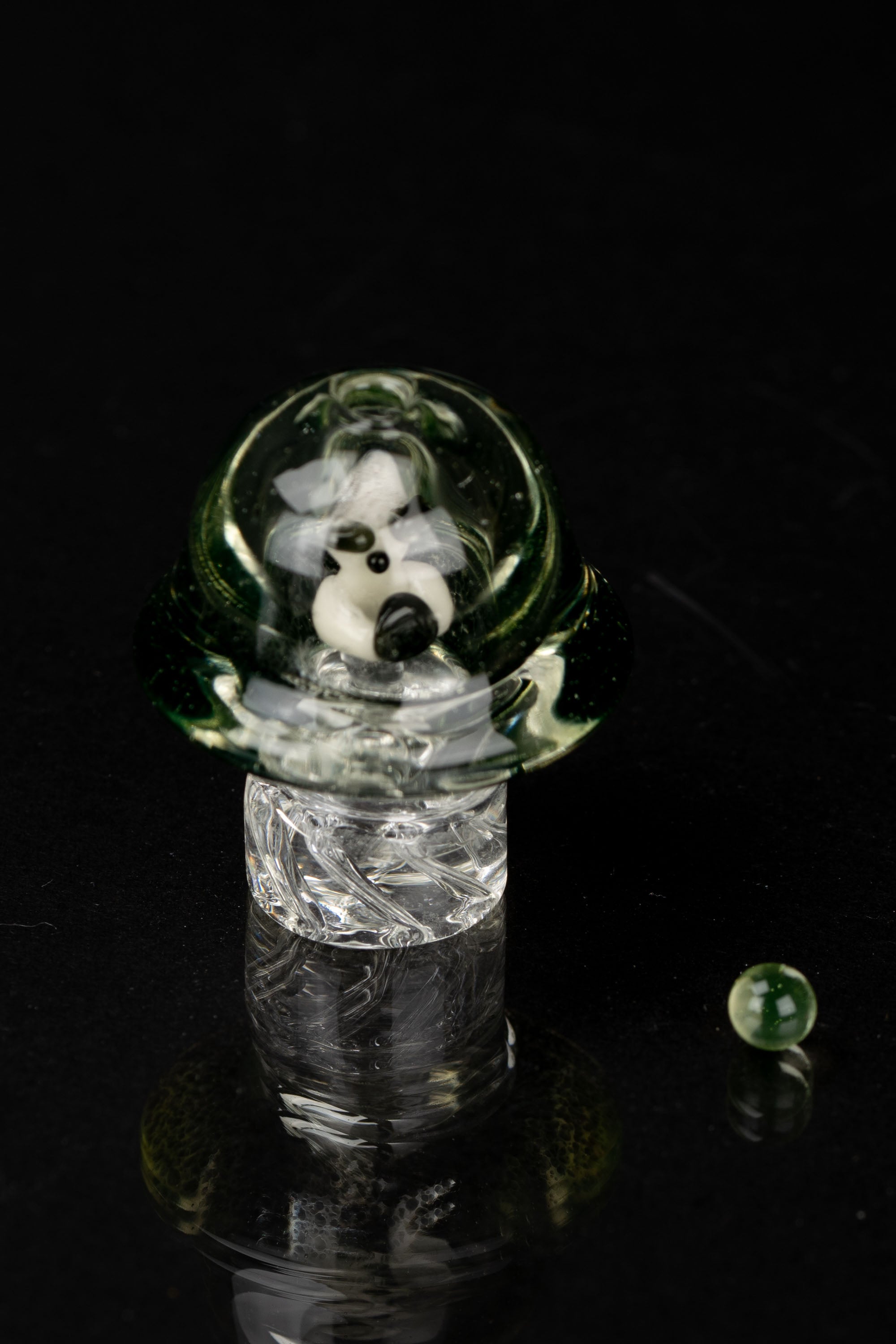 A clear glass pipe with swirling green and white patterns, set against a black background.