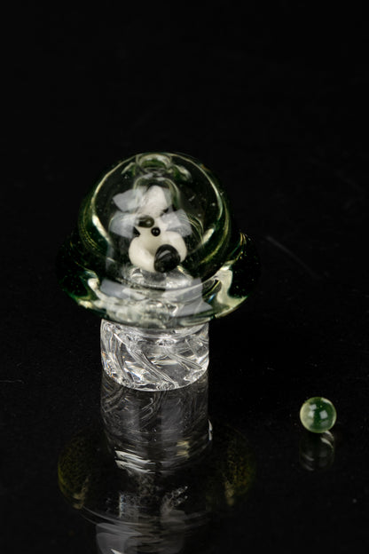 A clear glass pipe with swirling green and white patterns, set against a black background.