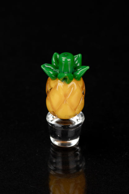 Glass pineapple-shaped oil rig bubbler against a black background.