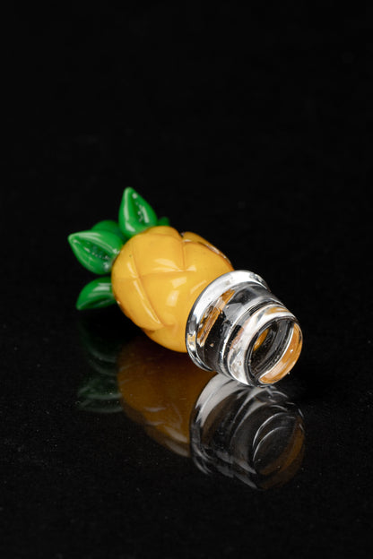 Hand-blown glass pineapple-shaped oil rig attachment with a clear mouthpiece, reflecting on a dark surface.