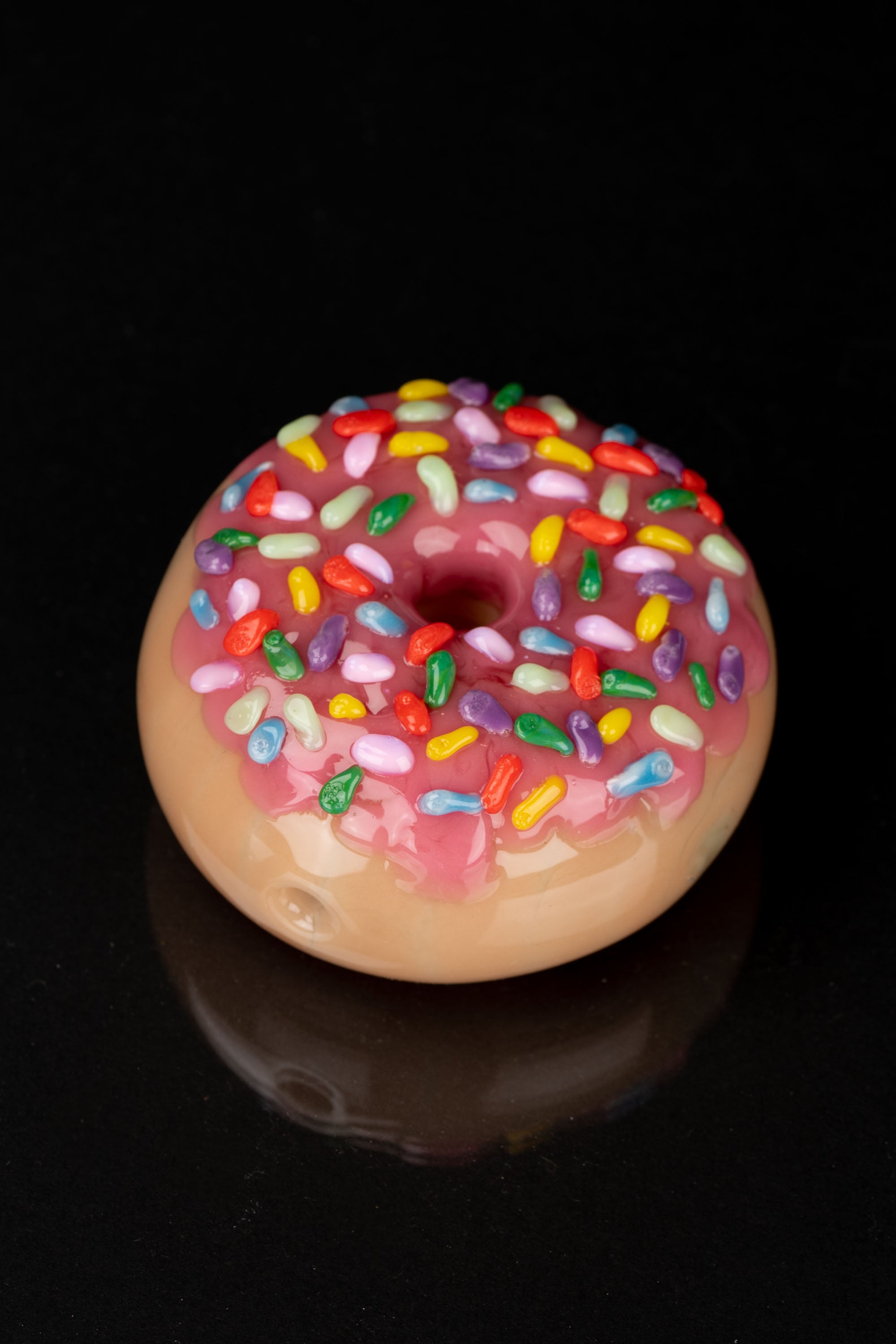 Pink glazed donut with colorful sprinkles, likely referencing cannabis-themed products.