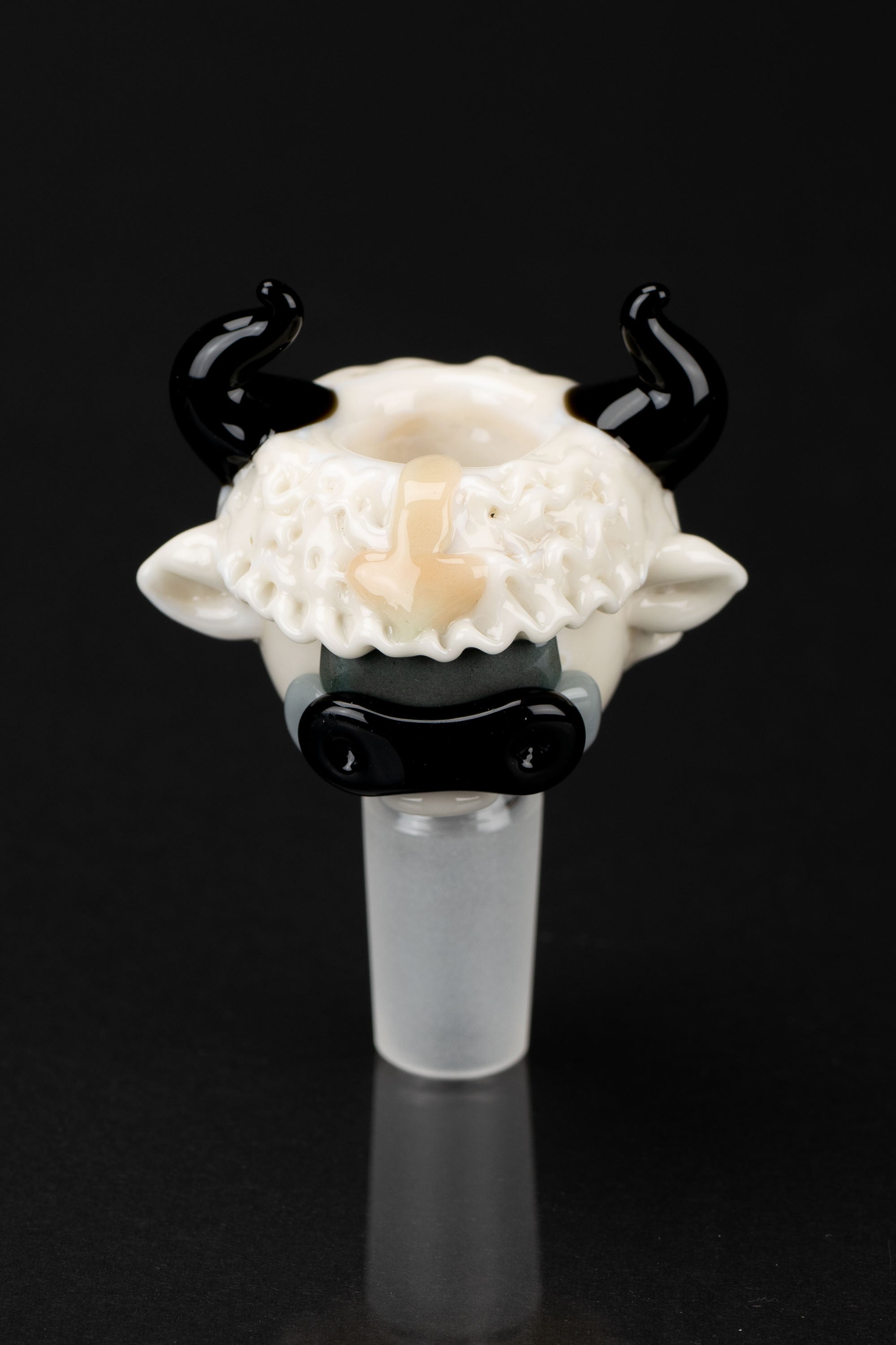 Glass cannabis pipe shaped like a cow's head with black horns, against a black background.