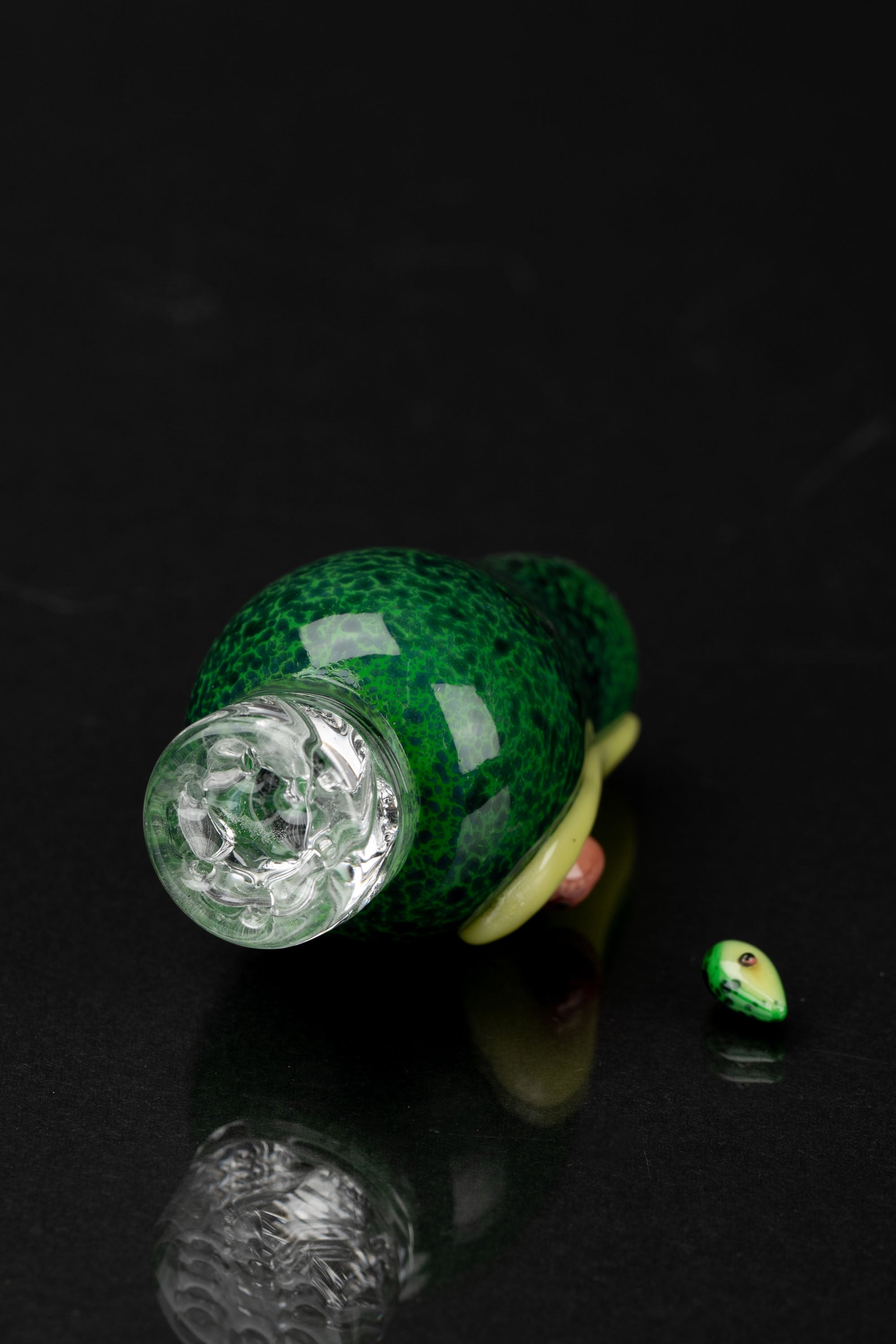 Green glass water pipe and small cannabis accessory on a dark surface.