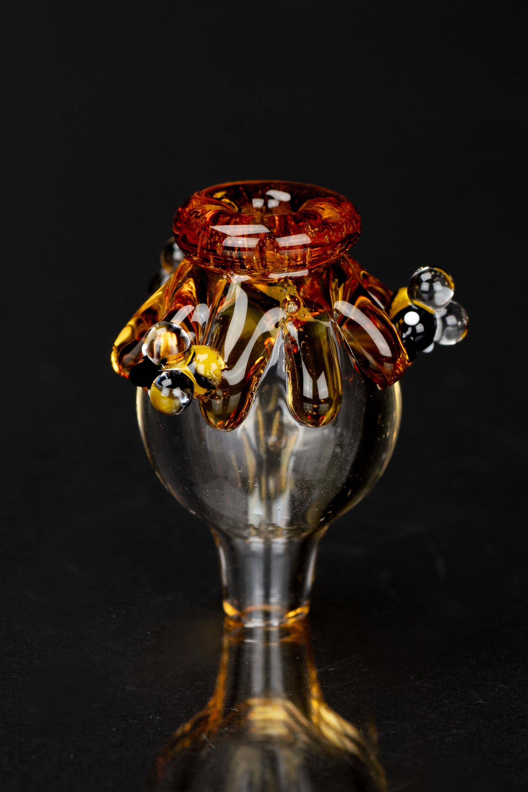 Amber glass cannabis oil rig dome with bubbles against a black background.