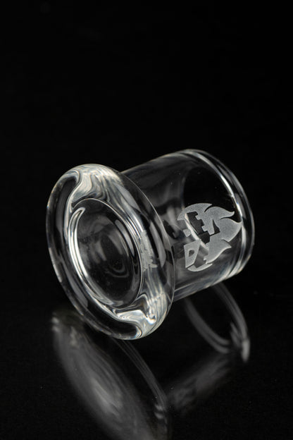 Clear glass cannabis concentrate container with etched logo, isolated on black.