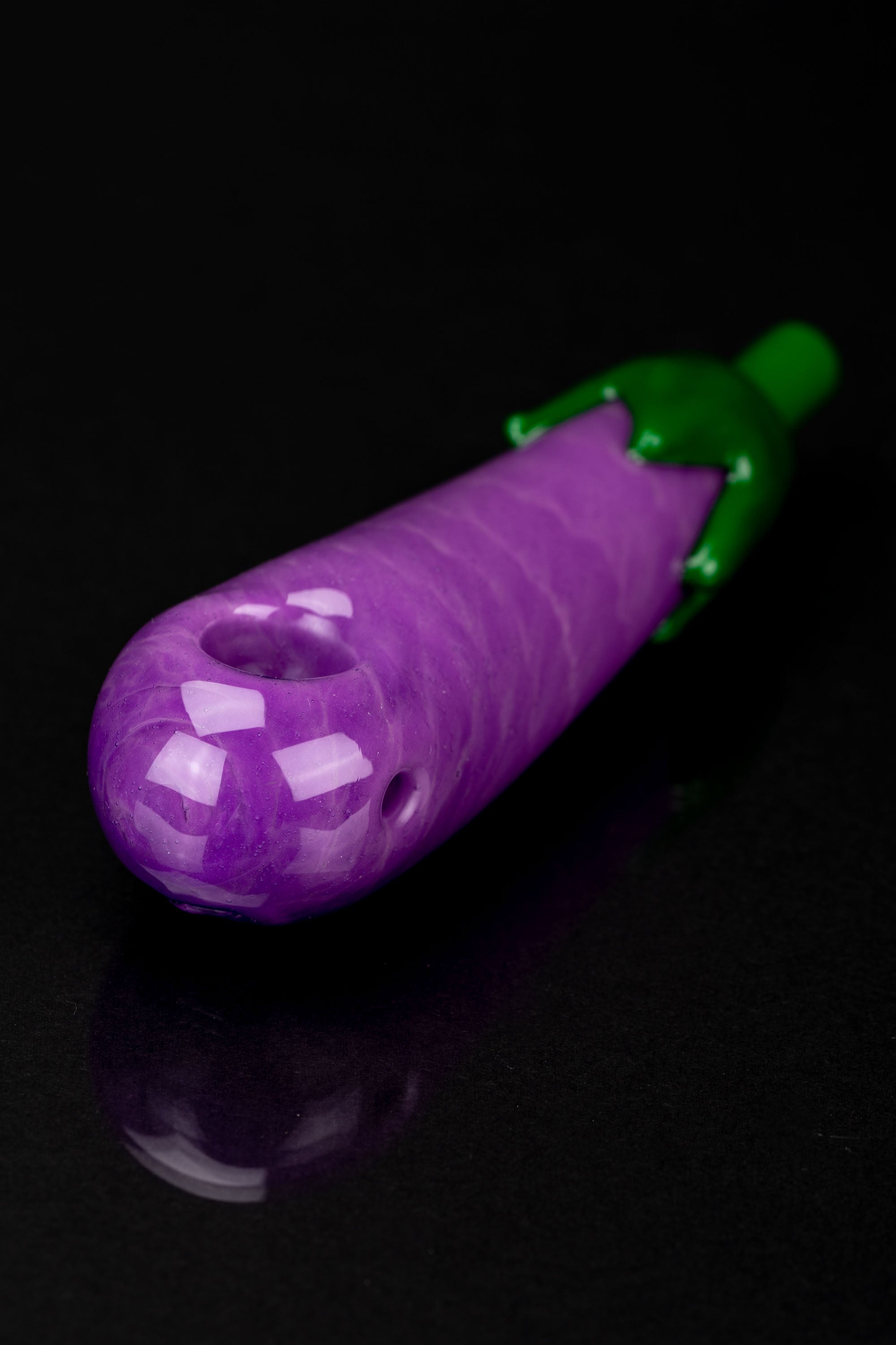 Purple glass pipe shaped like an eggplant against a black background.