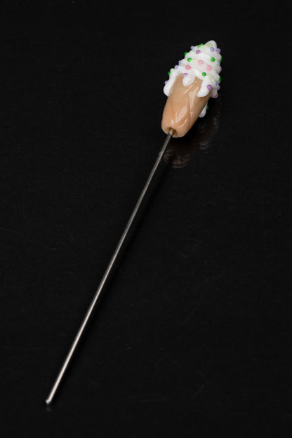 A glass dab tool resembling a chocolate-covered strawberry with colorful sprinkles, against a black background.